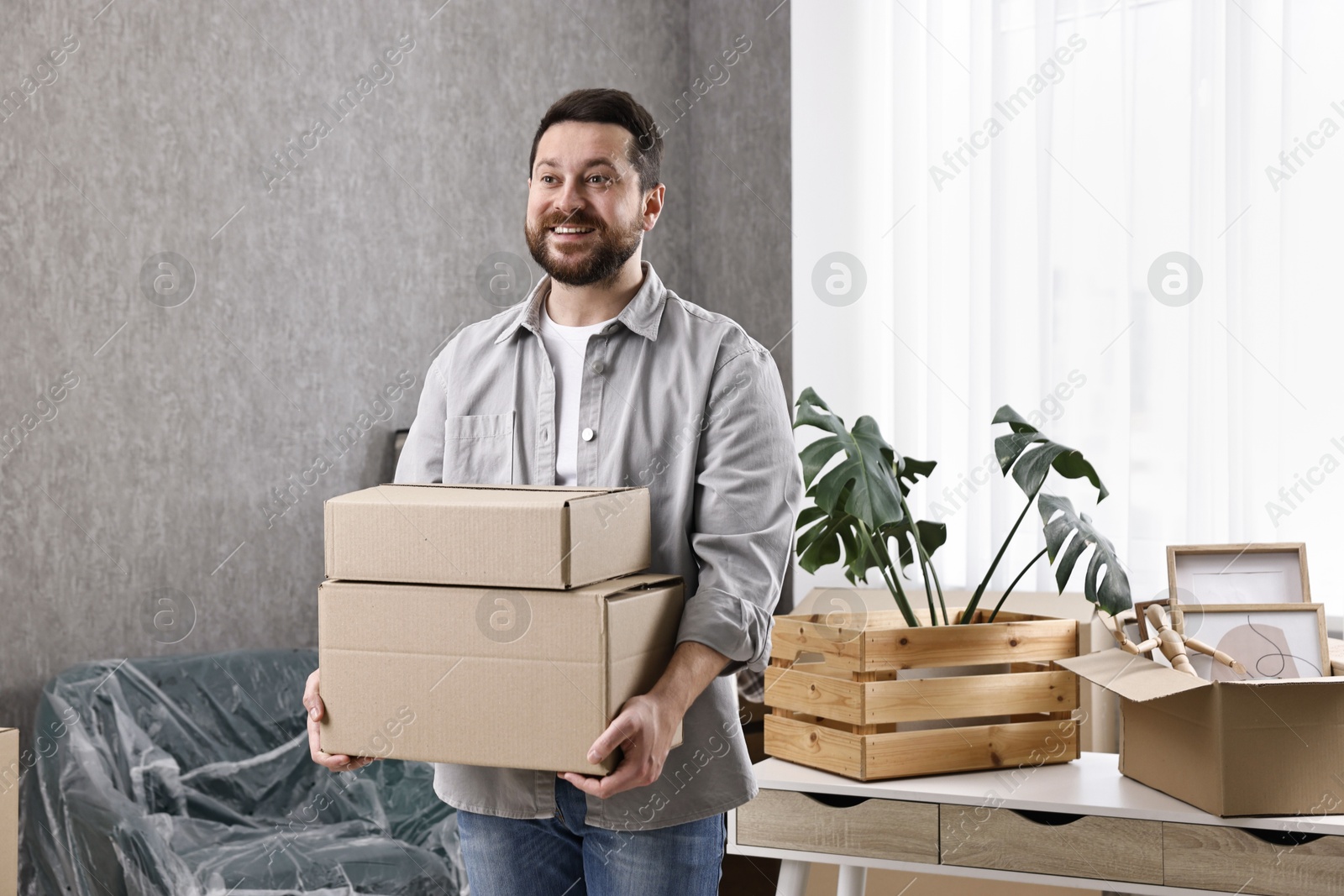 Photo of Moving day. Man with cardboard boxes in his new home