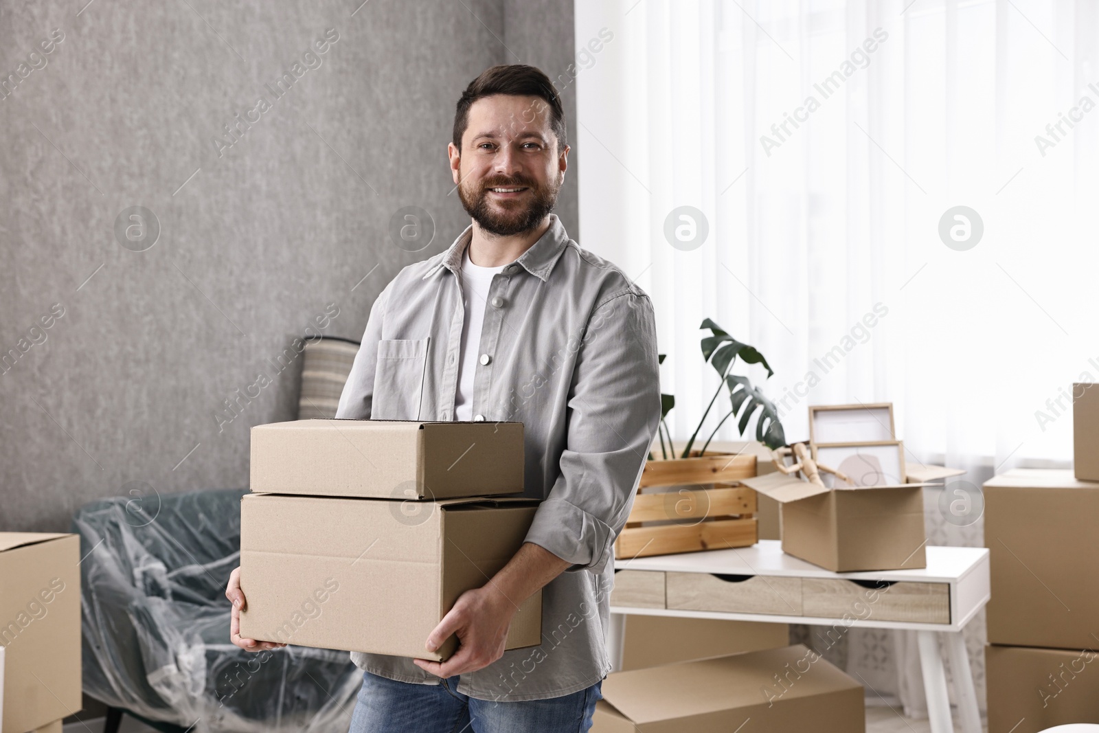 Photo of Moving day. Man with cardboard boxes in his new home