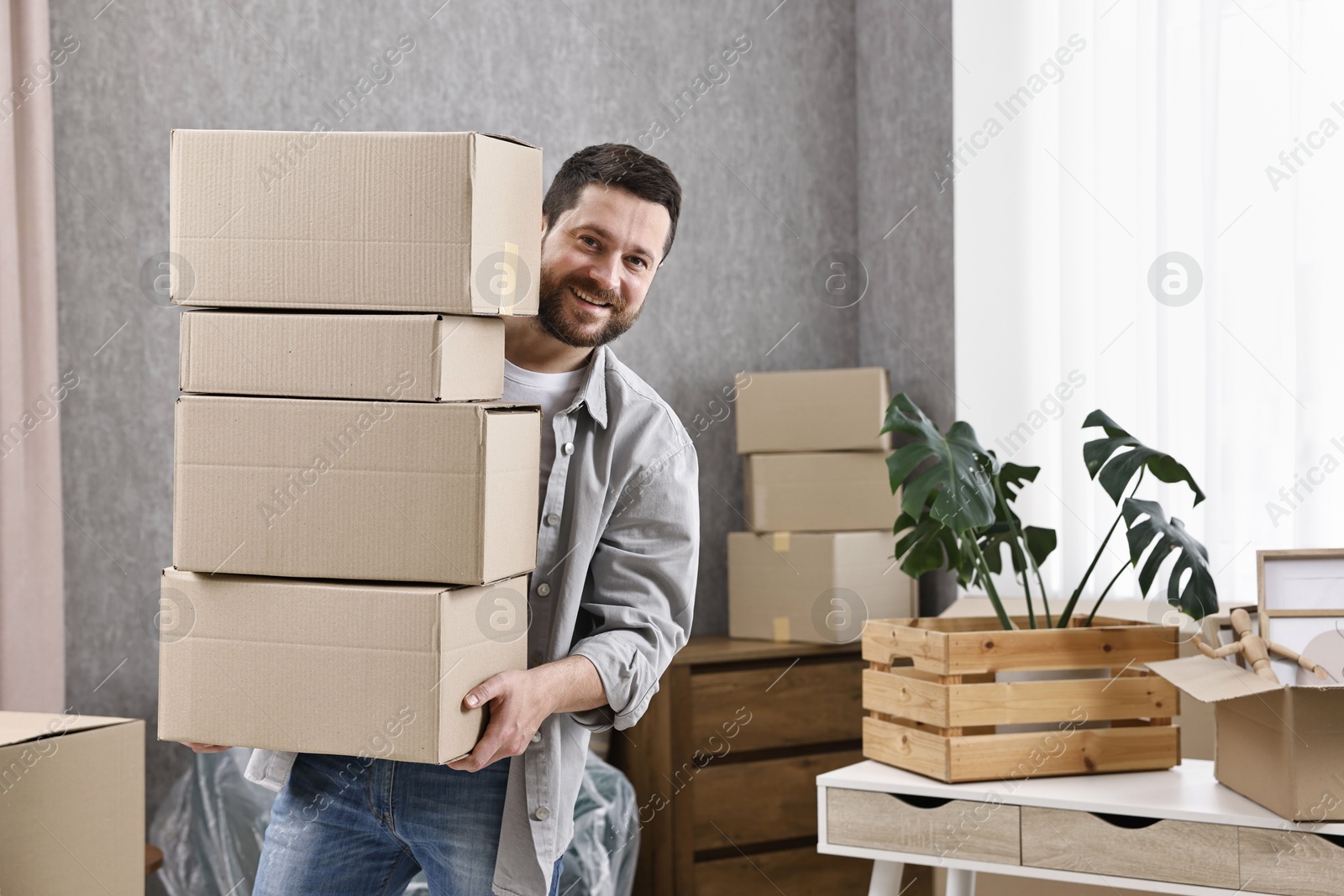 Photo of Moving day. Man with cardboard boxes in his new home