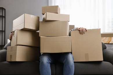 Moving day. Man with cardboard boxes on sofa in his new home