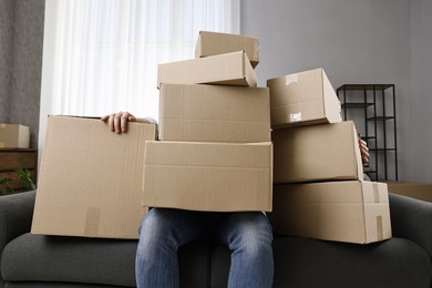 Moving day. Man with cardboard boxes on sofa in his new home