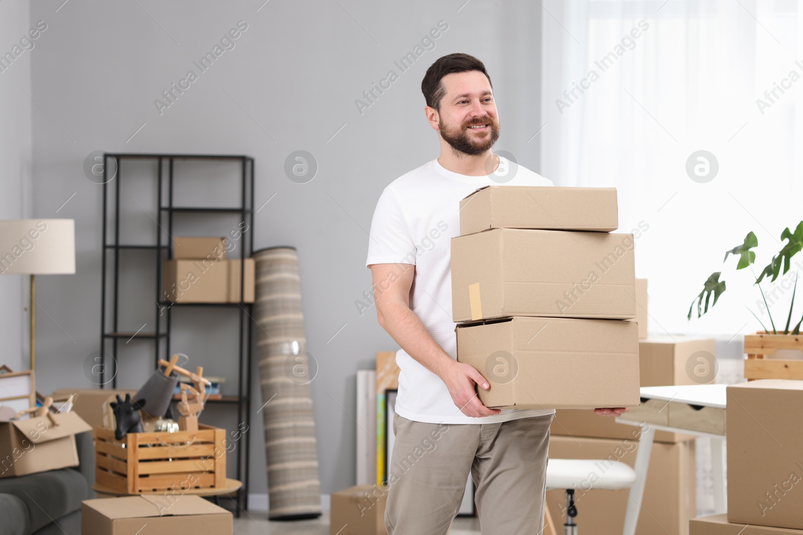 Photo of Moving day. Man with cardboard boxes in his new home