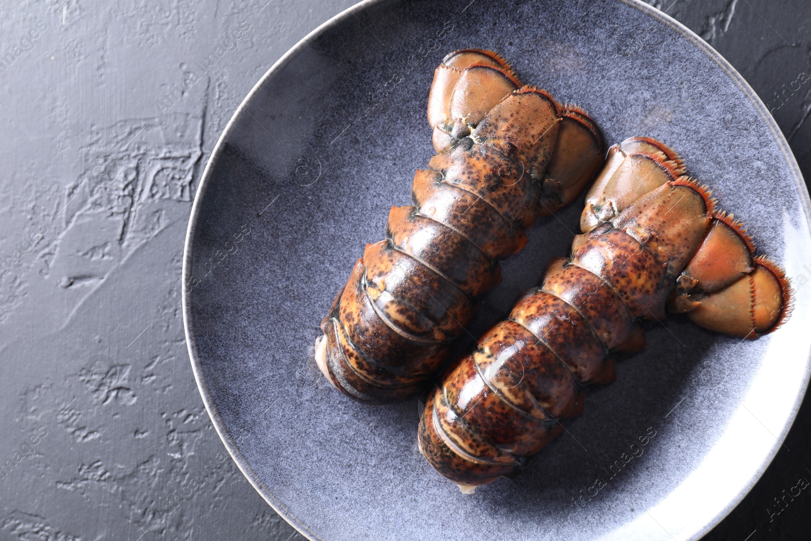 Photo of Raw lobster tails on black table, top view