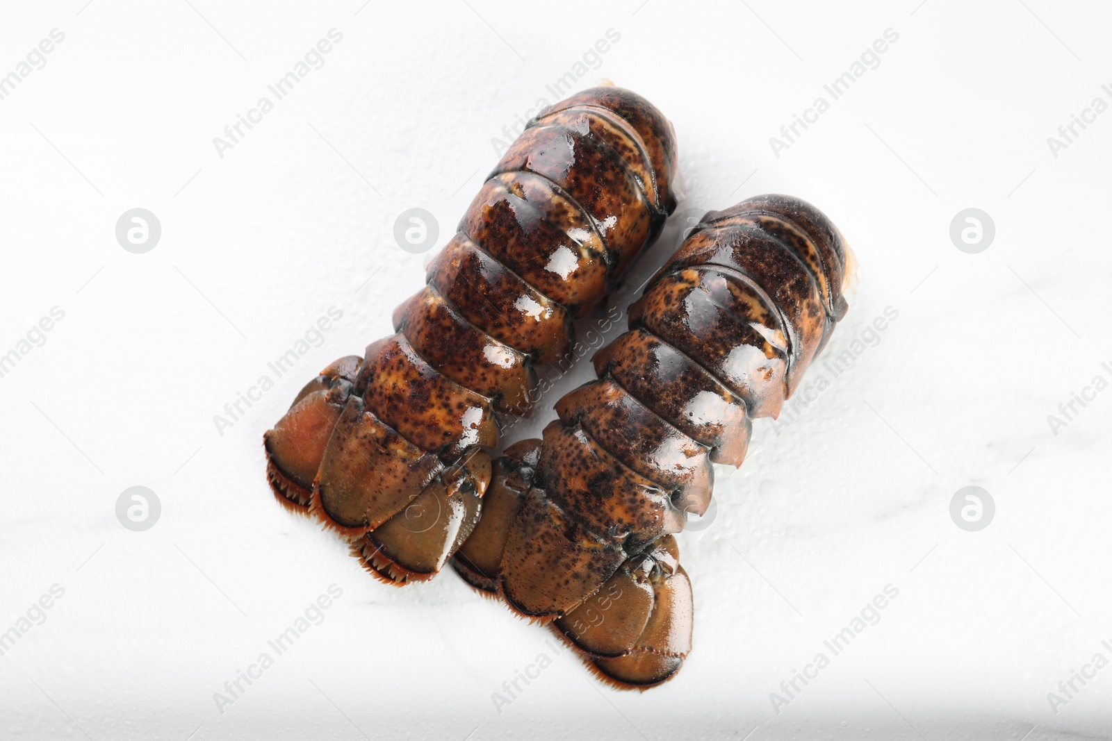 Photo of Raw lobster tails on white table, flat lay