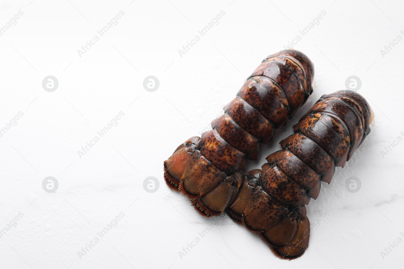 Photo of Raw lobster tails on white table, flat lay. Space for text