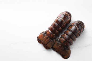 Photo of Raw lobster tails on white table, flat lay. Space for text