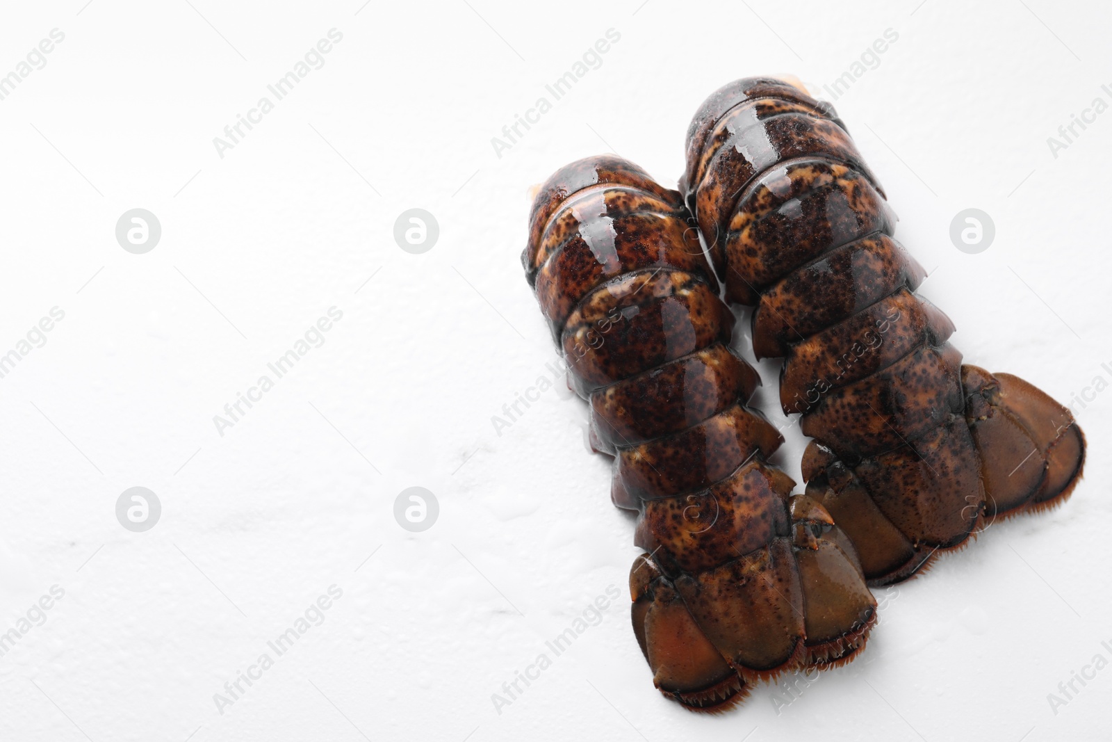 Photo of Raw lobster tails on white table, flat lay. Space for text