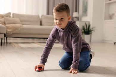 Photo of Little boy playing with toy car at home