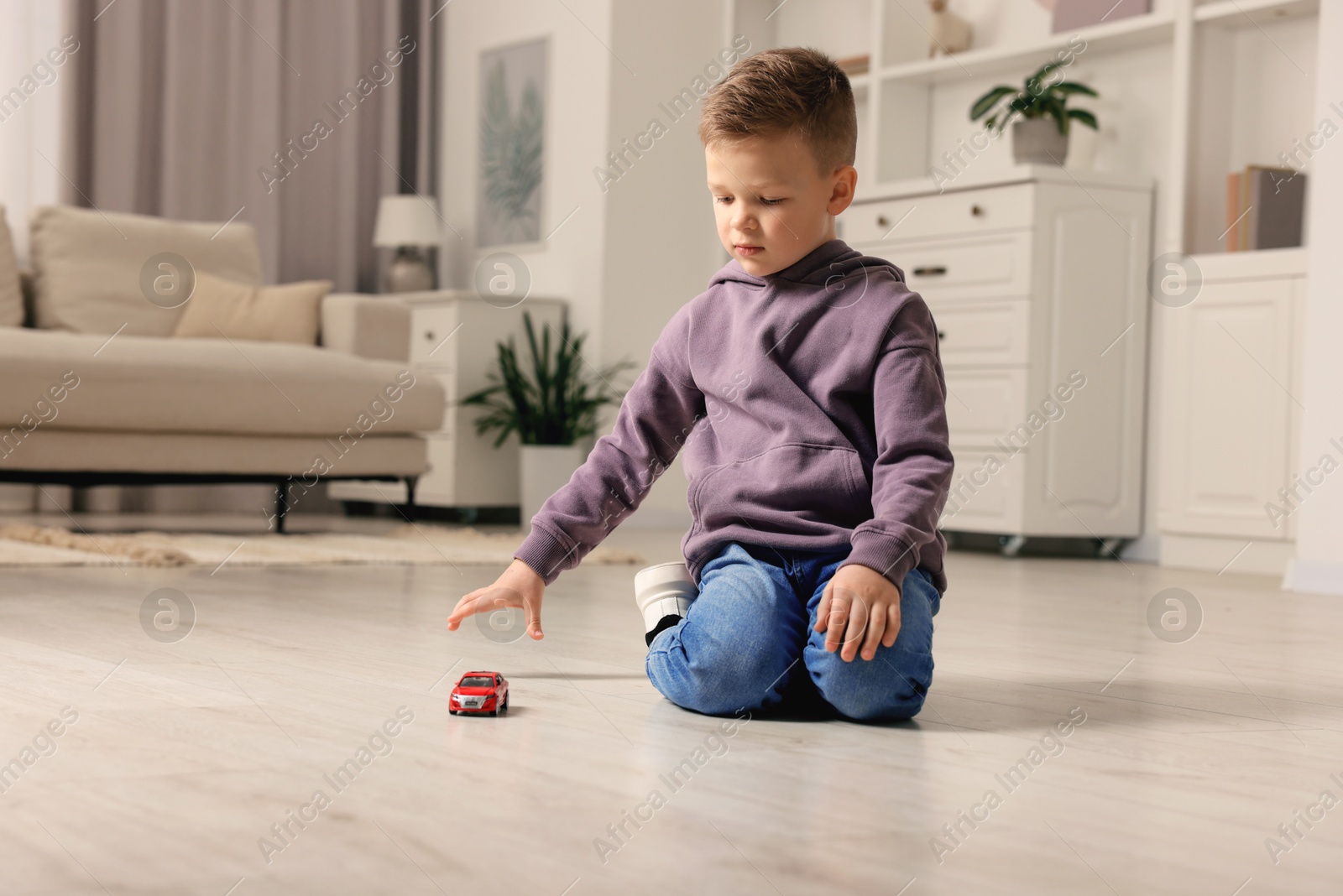 Photo of Little boy playing with toy car at home