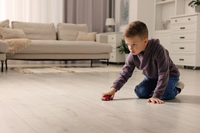 Photo of Little boy playing with toy car at home. Space for text