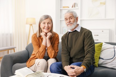 Portrait of happy elderly couple on sofa at home