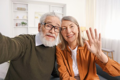 Photo of Happy elderly couple taking selfie at home