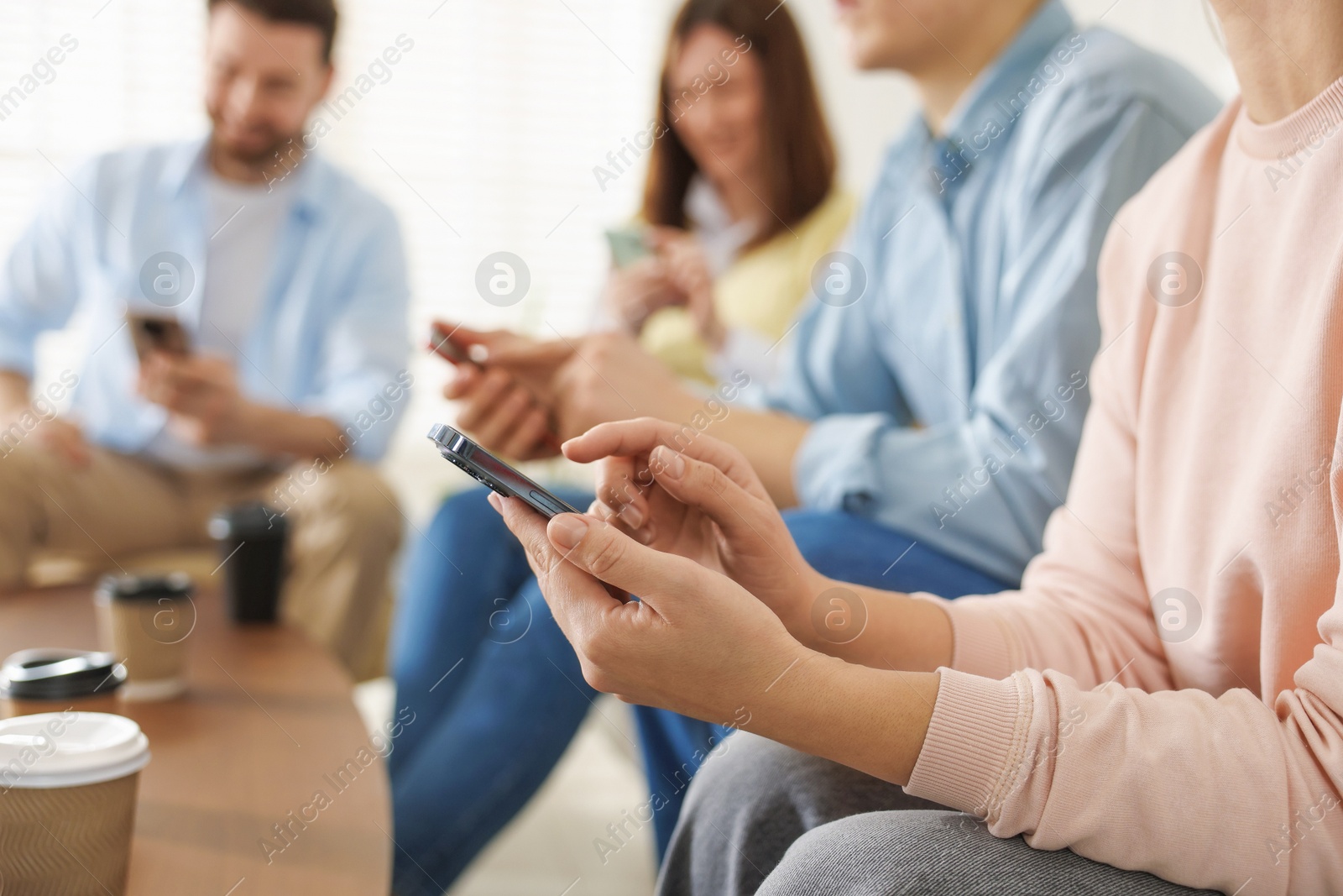 Photo of Internet addiction. Group of people with smartphones and coffee at table indoors, closeup