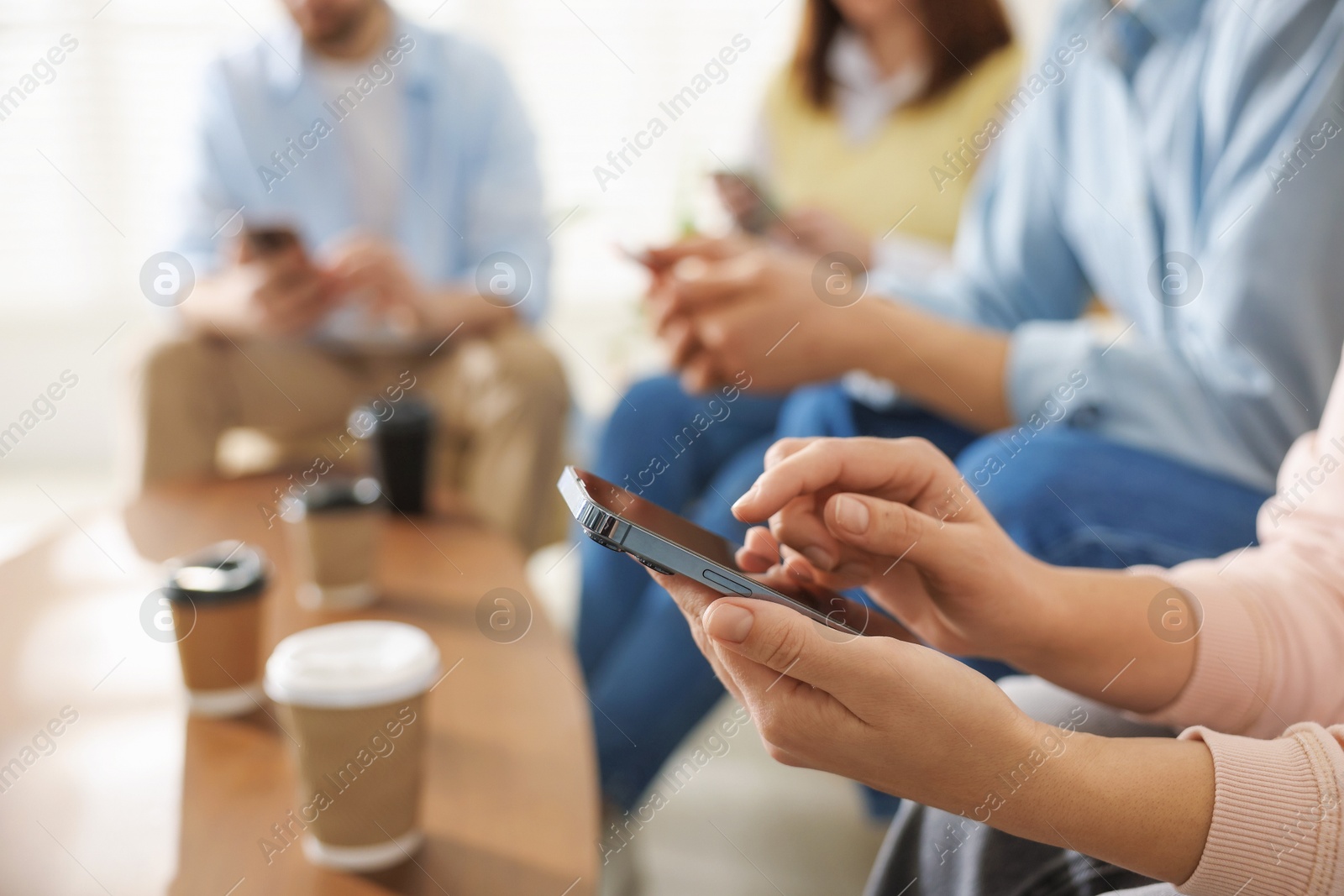 Photo of Internet addiction. Group of people with smartphones and coffee at table indoors, closeup