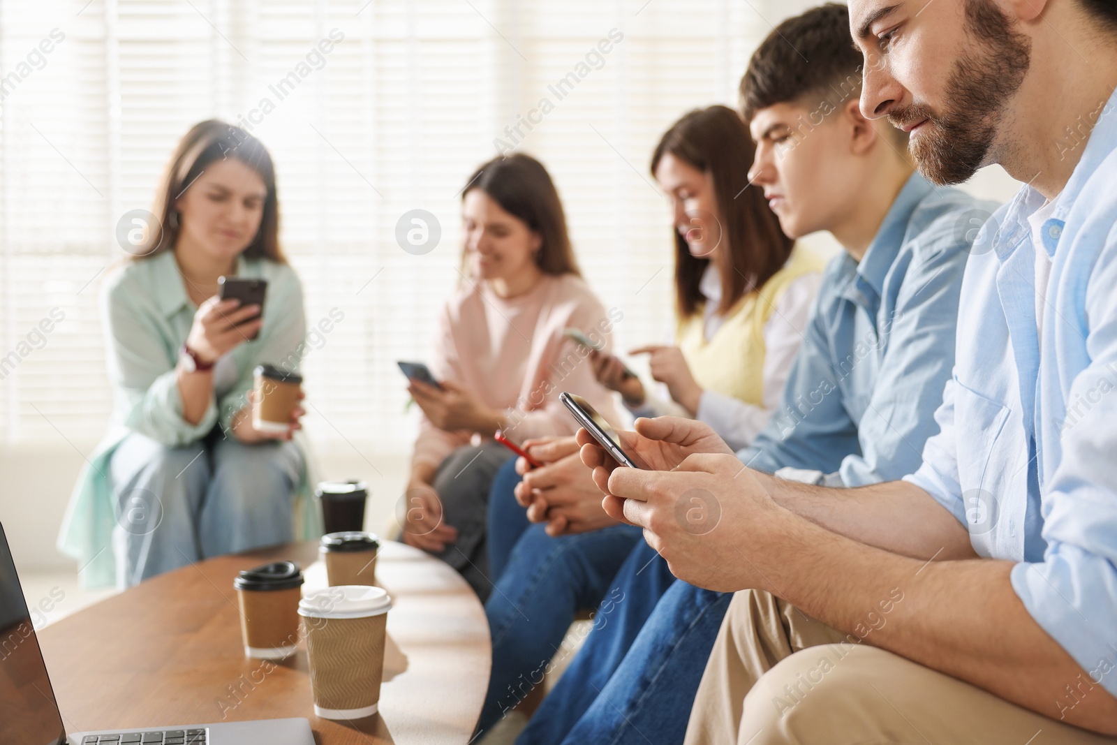 Photo of Internet addiction. Group of friends with gadgets and coffee at table indoors