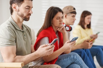 Internet addiction. Group of people with smartphones indoors