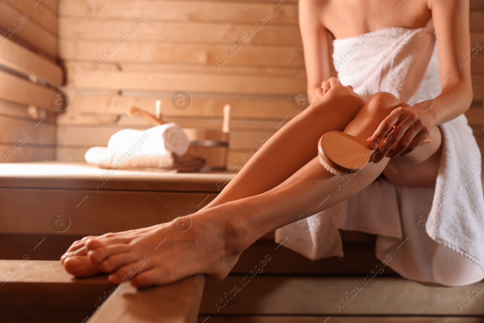 Photo of Woman massaging her leg with brush at sauna, closeup. Space for text