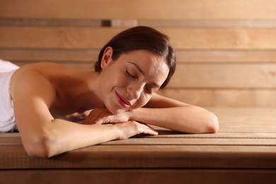 Beautiful woman relaxing on bench at sauna