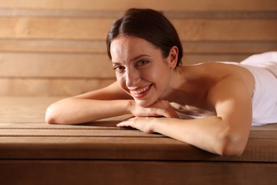 Photo of Smiling woman relaxing on bench at sauna