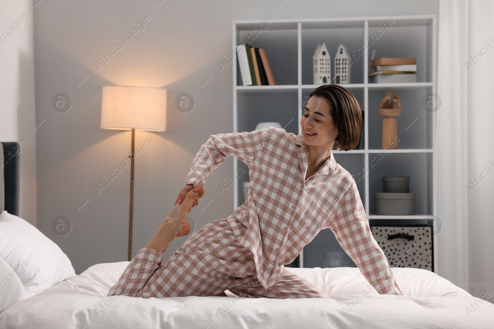 Photo of Young woman exercising on bed at home. Morning routine