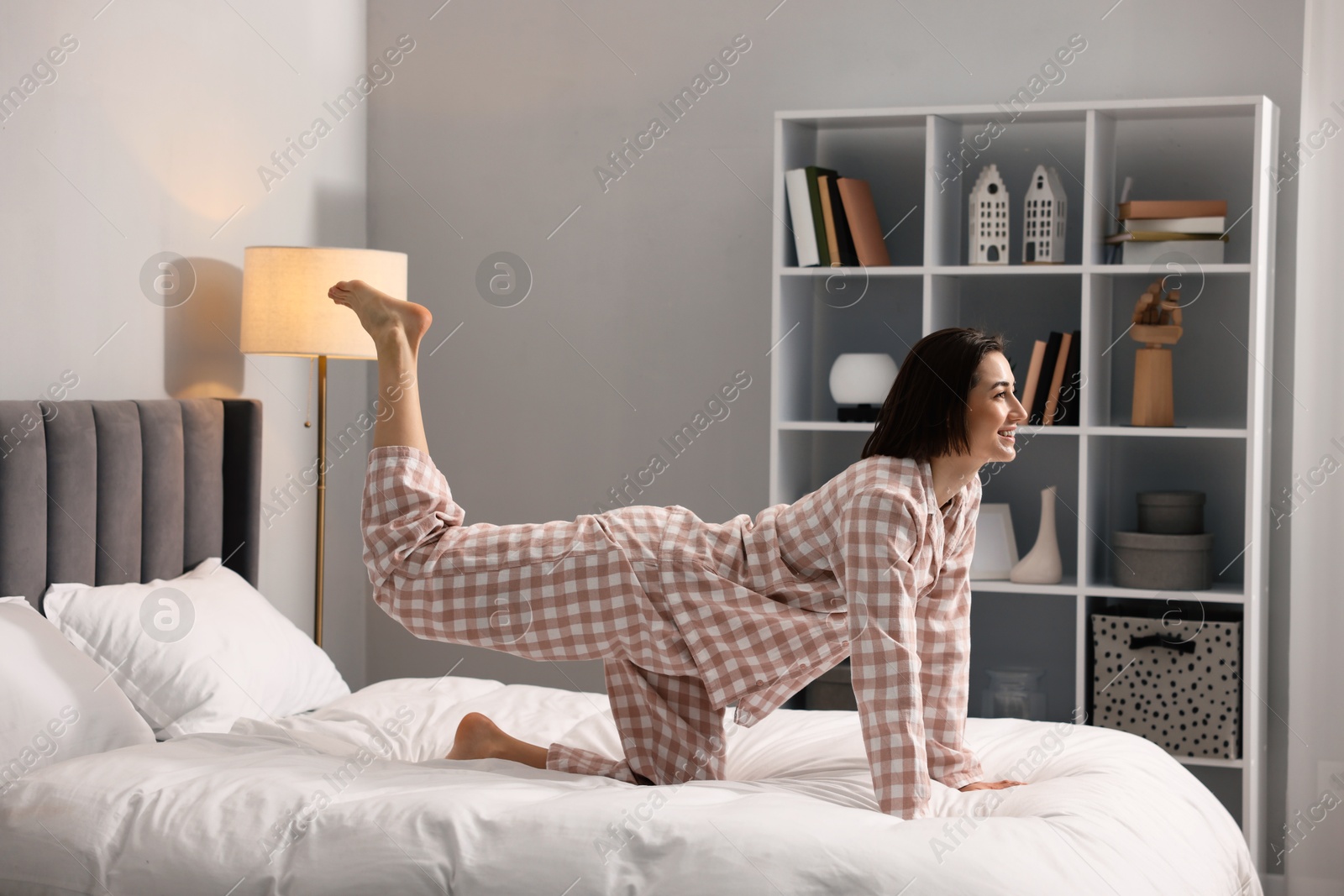 Photo of Young woman exercising on bed at home. Morning routine