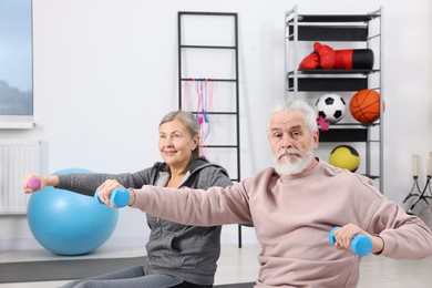 Elderly couple exercising with dumbbells at home