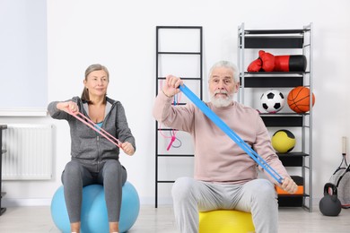 Photo of Elderly couple exercising with elastic bands and fitness balls at home