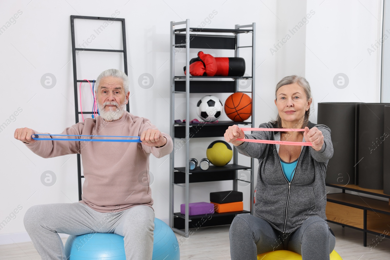 Photo of Elderly couple exercising with elastic bands and fitness balls at home