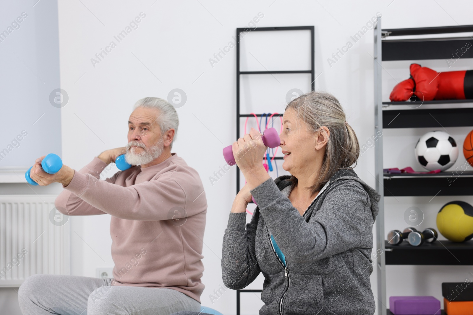 Photo of Elderly couple exercising with dumbbells at home