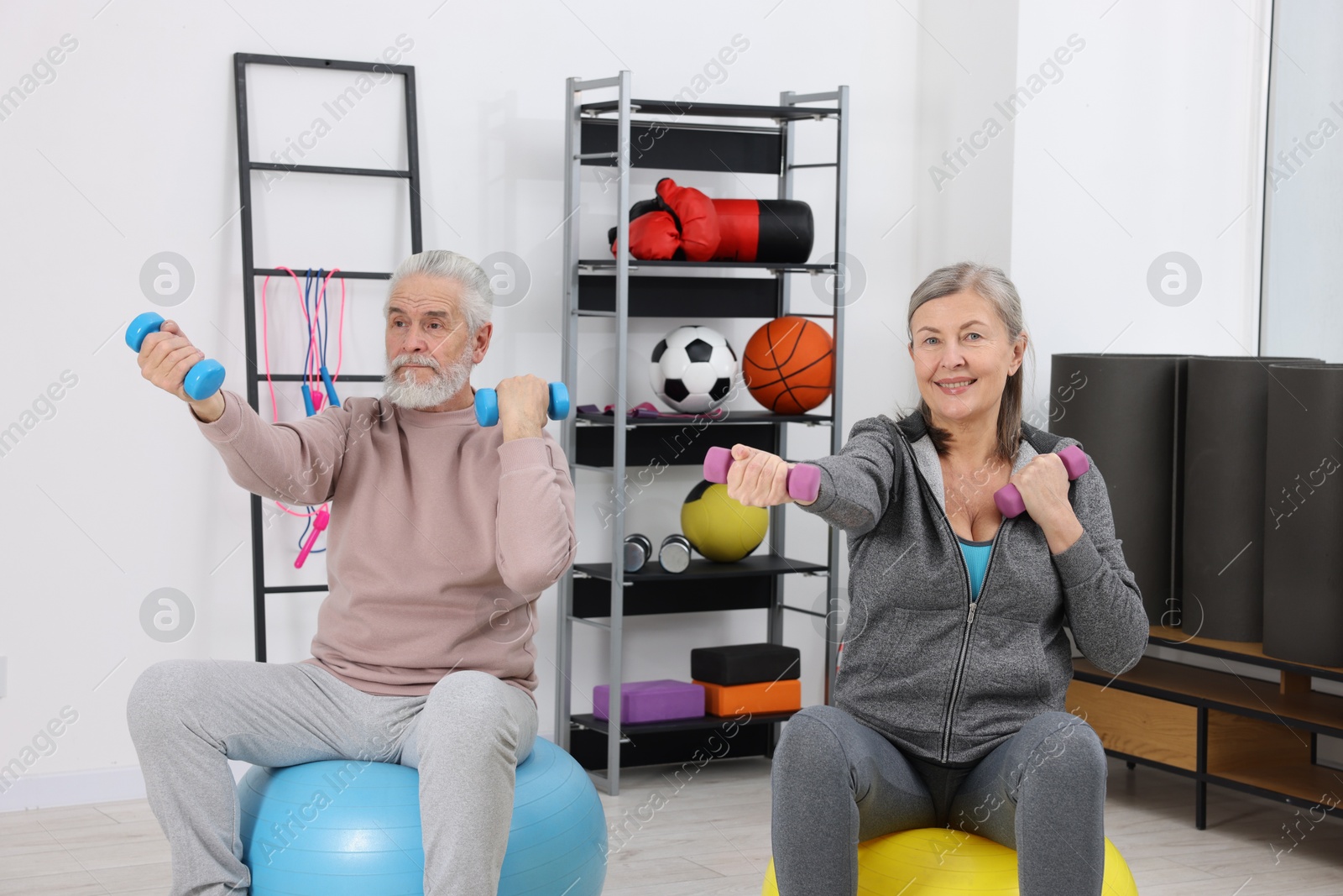 Photo of Elderly couple exercising with dumbbells and fitness balls at home