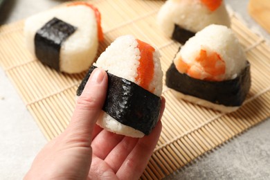 Photo of Woman with tasty onigiri (Japanese rice ball) at light table, closeup