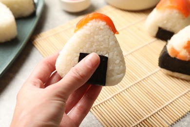 Photo of Woman with tasty onigiri (Japanese rice ball) at light table, closeup