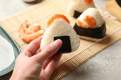 Photo of Woman with tasty onigiri (Japanese rice ball) at light table, closeup