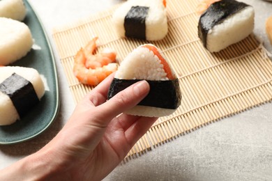 Photo of Woman with tasty onigiri (Japanese rice ball) at light table, closeup