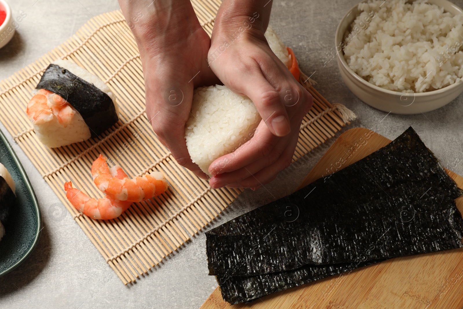 Woman making onigiri (Japanese rice balls) at light table, closeup Photo of Woman making onigiri (Japanese rice balls) at light table, closeup