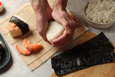Photo of Woman making onigiri (Japanese rice balls) at light table, closeup