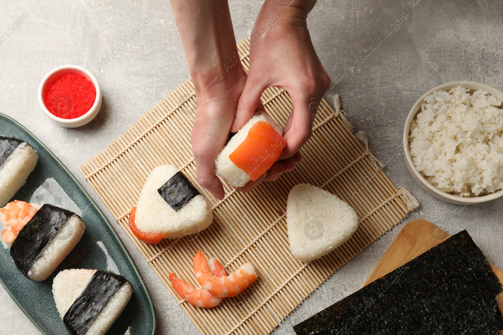 Woman making onigiri (Japanese rice balls) at light table, top view Photo of Woman making onigiri (Japanese rice balls) at light table, top view