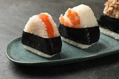 Photo of Tasty onigiri (Japanese rice balls) served on black table, closeup