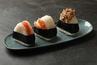 Photo of Tasty onigiri (Japanese rice balls) served on black table, closeup