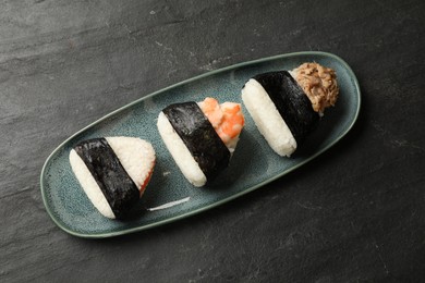 Photo of Tasty onigiri (Japanese rice balls) served on black table, top view