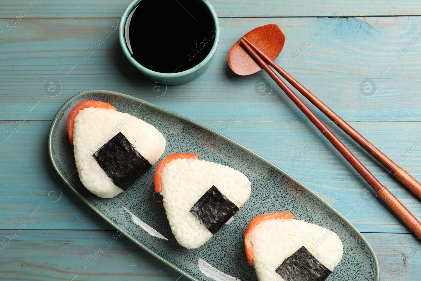 Photo of Tasty onigiri (Japanese rice balls) served on blue wooden table, flat lay