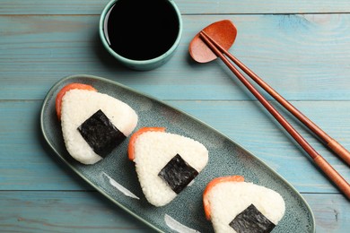 Photo of Tasty onigiri (Japanese rice balls) served on blue wooden table, flat lay