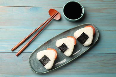 Photo of Tasty onigiri (Japanese rice balls) served on blue wooden table, flat lay
