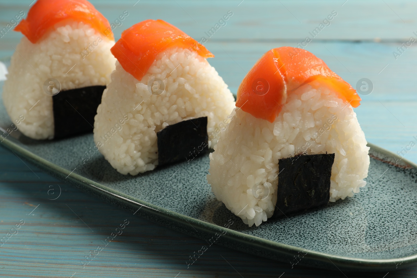 Tasty onigiri (Japanese rice balls) served on blue wooden table, closeup Photo of Tasty onigiri (Japanese rice balls) served on blue wooden table, closeup