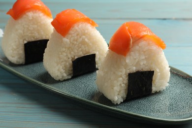 Photo of Tasty onigiri (Japanese rice balls) served on blue wooden table, closeup
