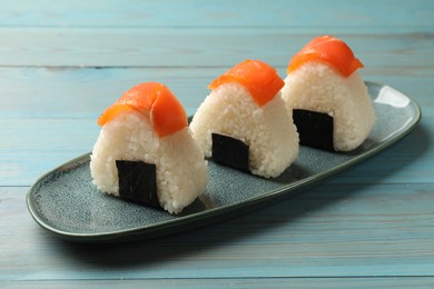 Photo of Tasty onigiri (Japanese rice balls) served on blue wooden table, closeup
