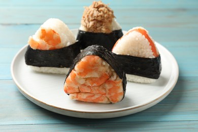 Photo of Tasty onigiri (Japanese rice balls) served on blue wooden table, closeup