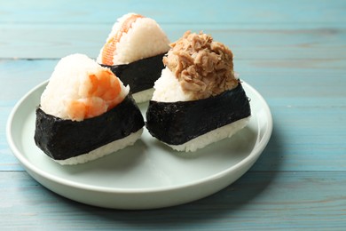 Photo of Tasty onigiri (Japanese rice balls) served on blue wooden table, closeup