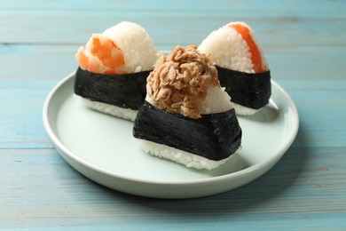 Photo of Tasty onigiri (Japanese rice balls) served on blue wooden table, closeup