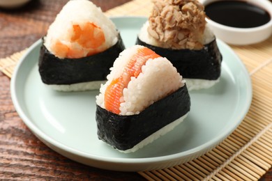 Photo of Tasty onigiri (Japanese rice balls) served on wooden table, closeup